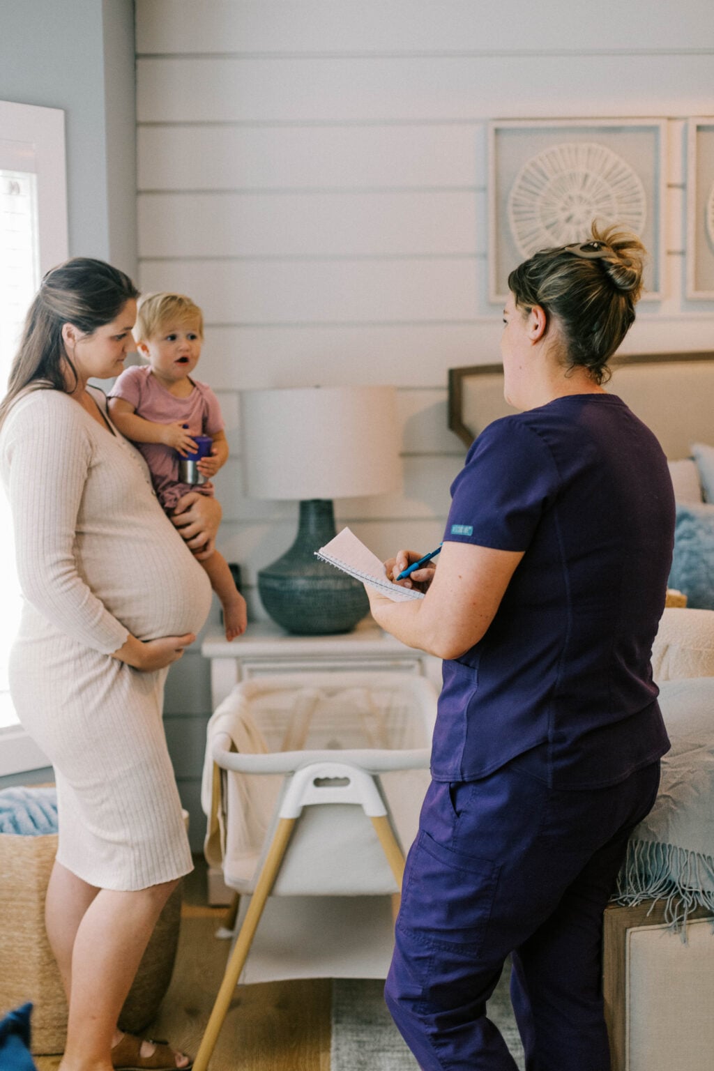 Newborn care specialist speaking with a parent holding a young child during a home visit