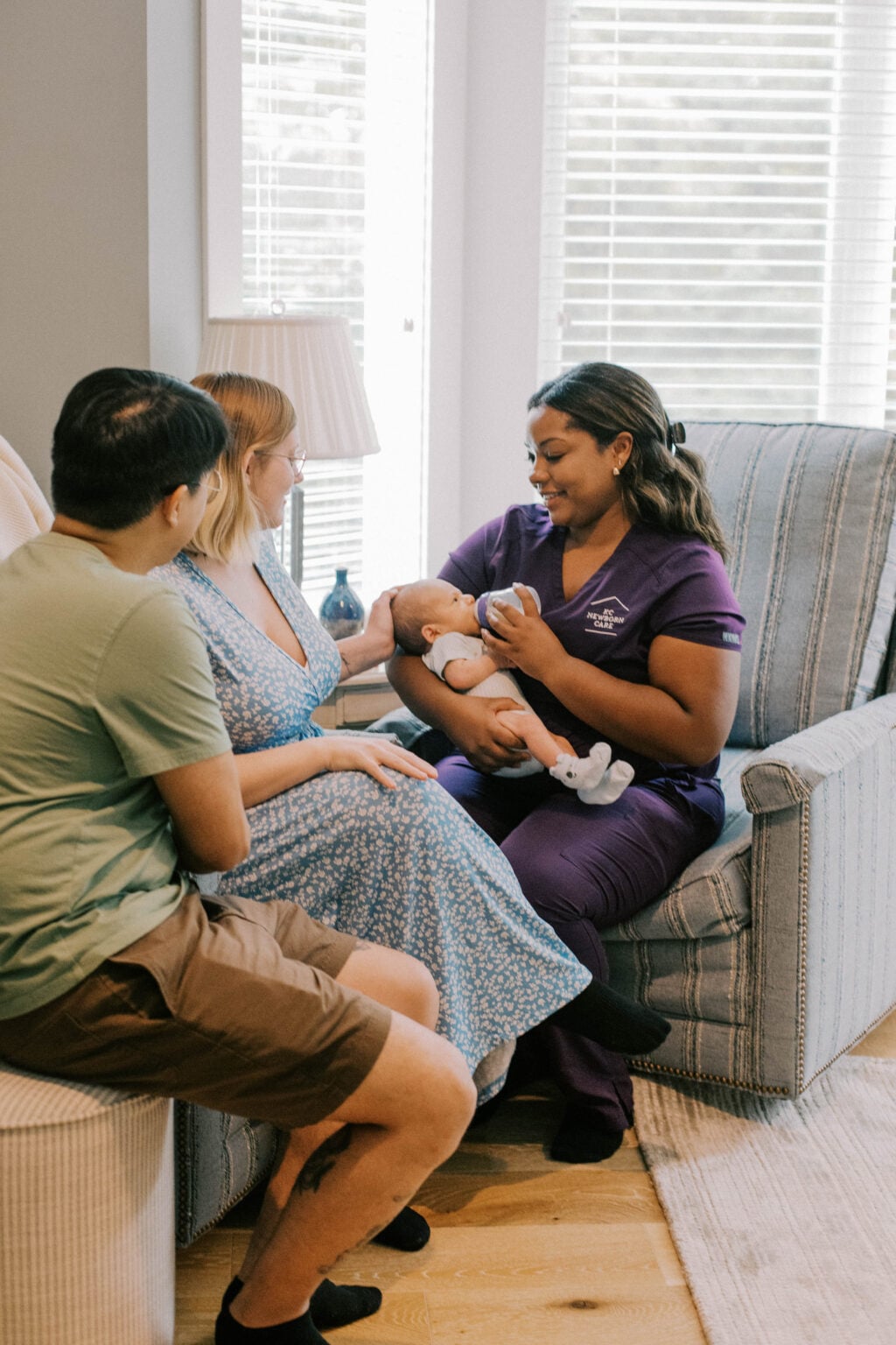 Newborn care specialist gently bottle-feeding a baby while parents sit close by